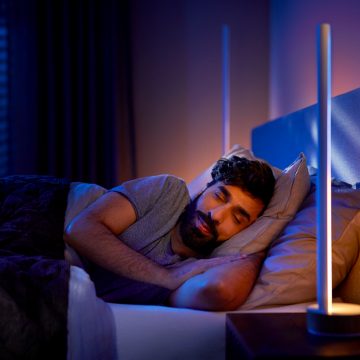 Uomo che dorme accanto alla lampada da comodino con luci soffuse