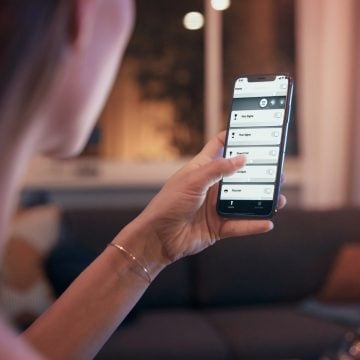 スマートライトアプリを表示している携帯電話を持つ女性