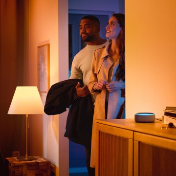 스마트 스피커를 가지고 집 안으로 걸어들어가는 남녀 