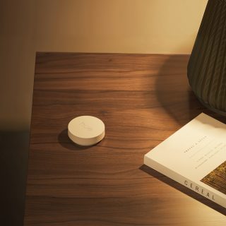화이트 Philips Hue smart button이 테이블 위, 노트북 옆에 놓여 있는 모습.