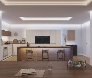 Een keuken verlicht met helder wit indirect licht van striplampen die zijn weggewerkt onder aanrechtbladen en plafond- en muurkoven om een wandwaseffect te creëren. 
