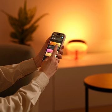 A smart lamp being dimmed using the Hue app on a smartphone.