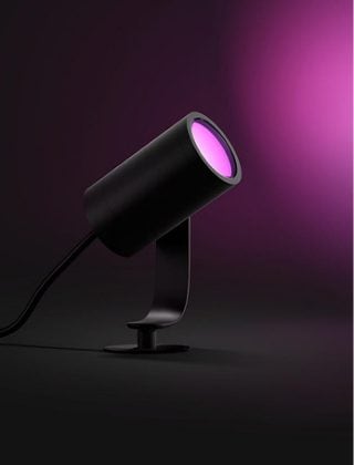 Czarny reflektor Philips Hue Lily świecący różowym światłem. 