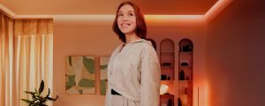 Uma mulher está em uma sala de estar iluminada com lâmpadas e luzes Philips Hue.