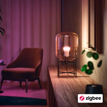 Lâmpada inteligente Philips Hue ajustada para branco quente num candeeiro numa mesa de apoio