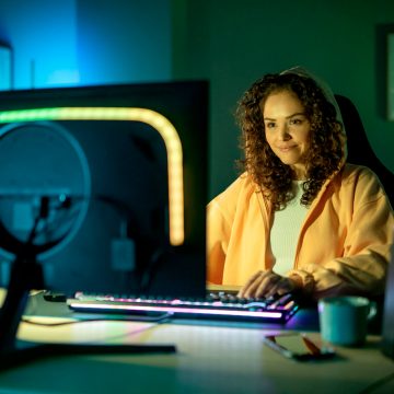 Mulher jogando num computador com luzes inteligentes coloridas adicionadas ao seu monitor
