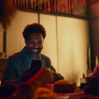 Homem sorridente a verificar o sistema de segurança de domótica no smartphone
