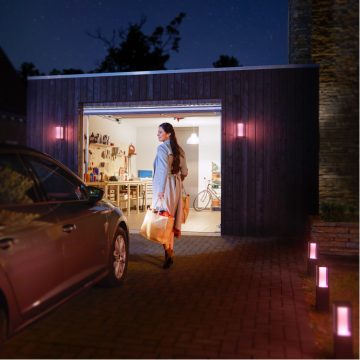 Mulher com um saco de compras a caminhar do carro até a garagem com iluminação brilhante